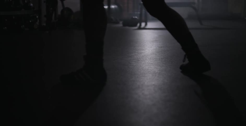 A woman swings back and forth in a dark gym