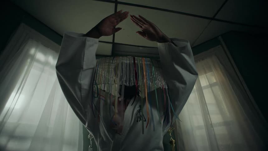 Three masked figures in martial arts uniforms engage in a surreal sparring match in a dimly lit room