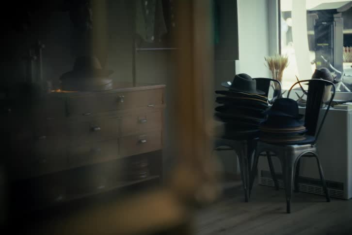 Atmospheric static shot of a vintage hat shop with fedoras stacked on chairs and furniture