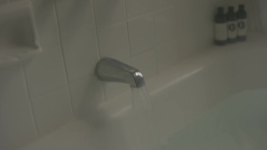 Person turns the bath faucet off