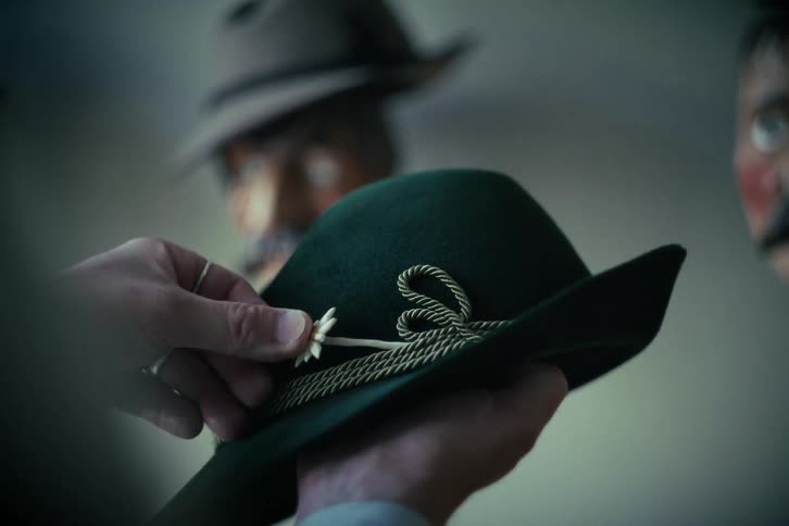 The finishing touch of an edelweiss flower is carefully added to a classic green Tyrolean hat