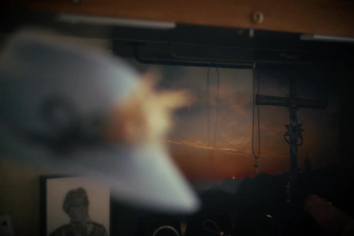 A close-up rack focus from a photograph of a crucifix at sunset to a vintage blue hat on a shelf