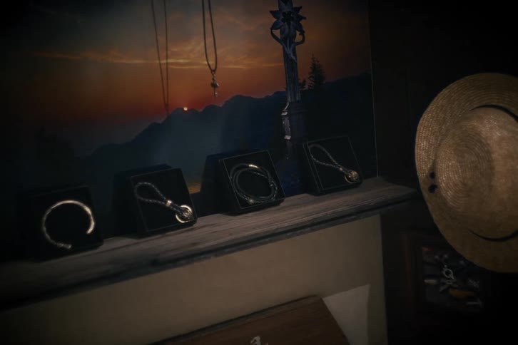 A moody still life shot of men's bracelets and necklaces displayed on a shelf in front of a scenic poster