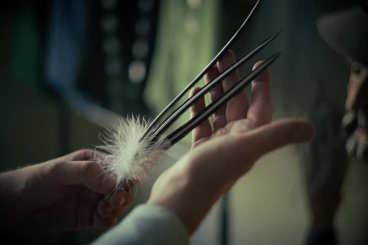 An artisan carefully arranges a set of black and white bird feathers in a dimly lit workshop