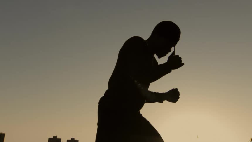 Cinemagraph of a man's silhouette in a fighting stance against a golden sunset sky over a distant city