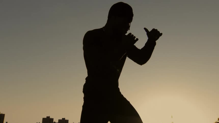 Cinemagraph of a man in a boxing stance, silhouetted by the golden morning sun in the city