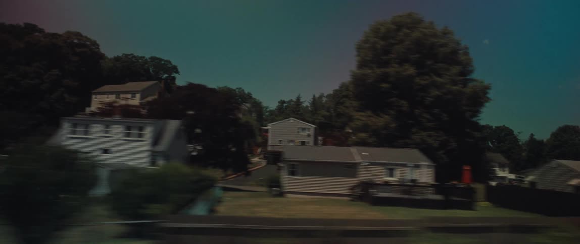 A stylized, fast-moving point-of-view shot of a suburban neighborhood with houses and trees on a sunny day