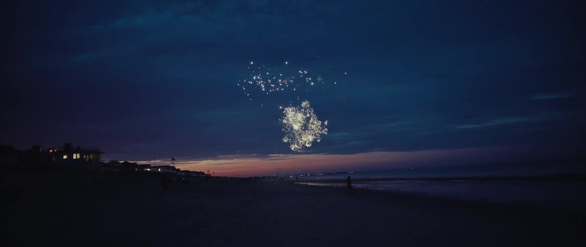 A beautiful display of fireworks lights up the twilight sky over a peaceful beach