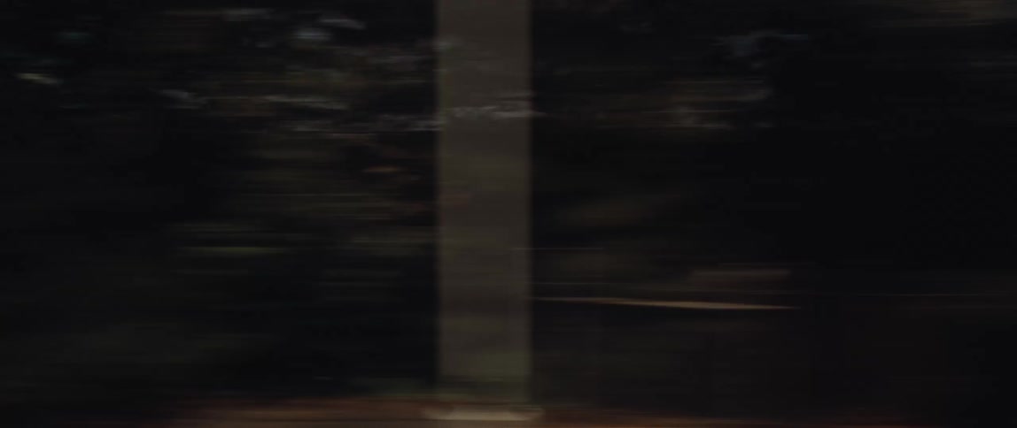 A motion-blurred side view from a moving vehicle captures the passing scenery of a coastal town and marina