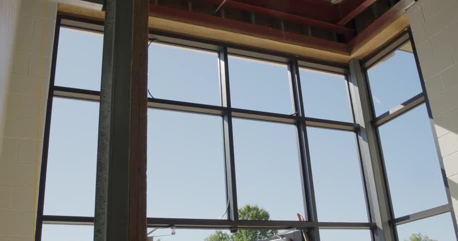 Slow zoom out from large, newly installed windows at an indoor construction site on a sunny day