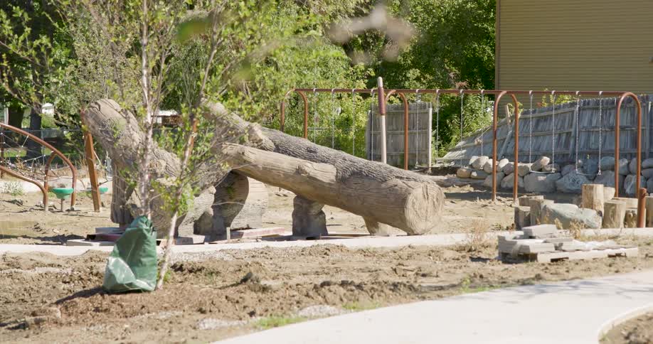 A slow zoom out of a natural playground featuring large log climbing equipment under construction in a park
