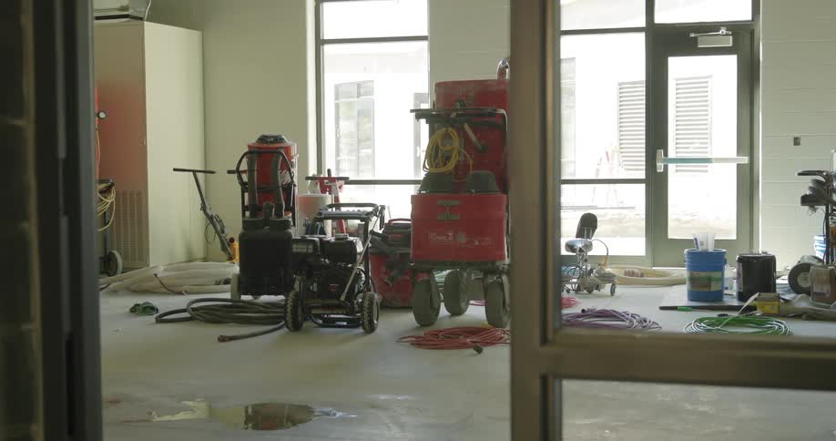 A collection of heavy-duty construction equipment and tools sits inside a building under construction