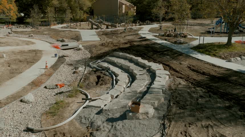 Aerial view pulling back from a stone amphitheater under construction in a new nature-themed park