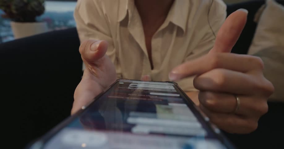 From a low angle, a person's fingers deftly type and scroll through a conversation on their smartphone