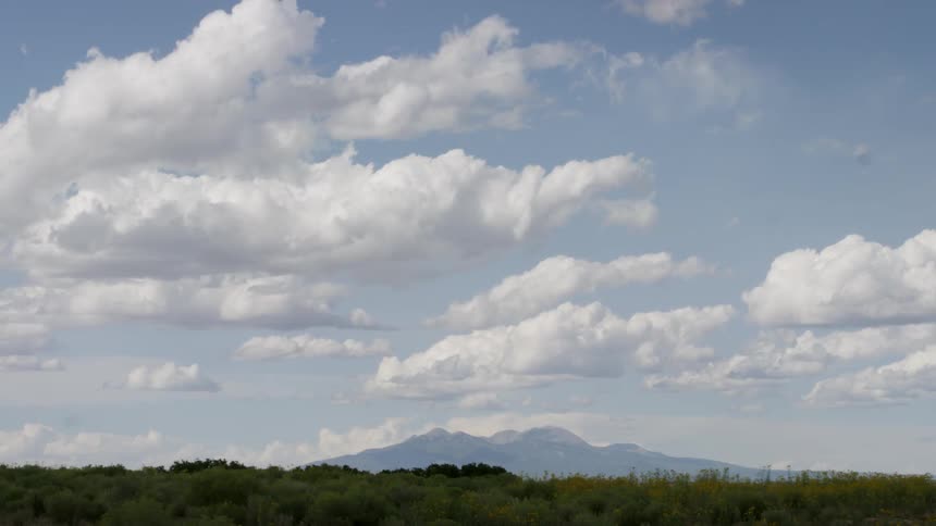 Clouds float over a field and mountains
