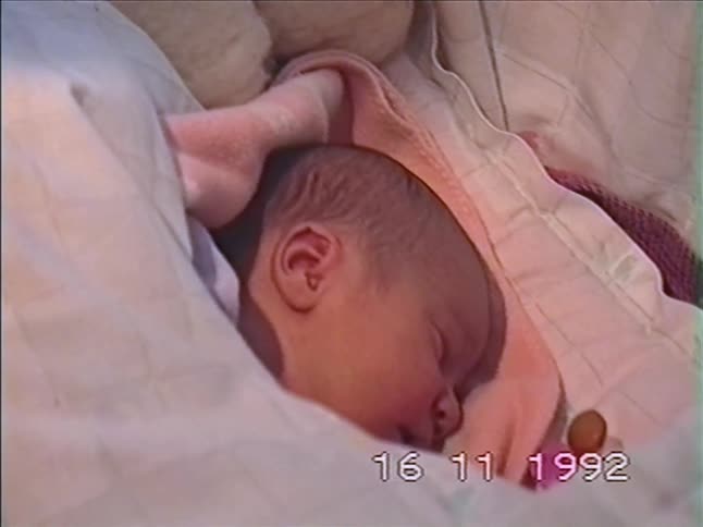 A newborn baby girl peacefully sleeps in her cozy crib in this vintage home video from 1992