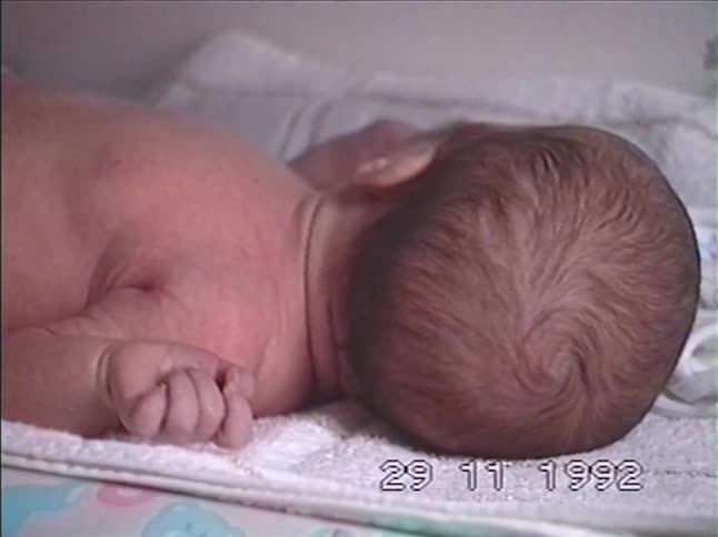A loving mother tenderly dries and cares for her newborn baby on a changing table in this nostalgic 1992 home video
