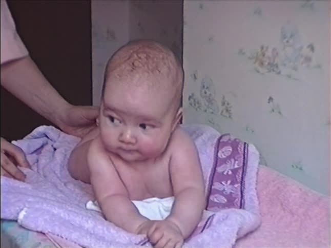 A gentle caregiver gives a newborn baby a relaxing massage while it lies on a changing table