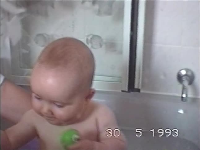 A vintage VHS home video from 1993 shows a cute baby with big eyes making a funny face while taking a bath