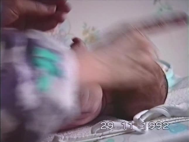 Vintage 1992 home video shows a tender moment as a mother changes and cares for her newborn baby on a changing table