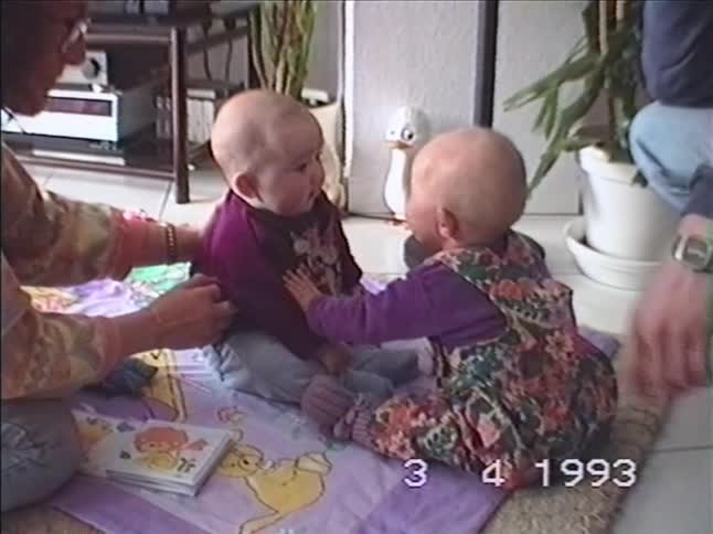 A vintage 1993 home video captures two babies sitting on a playmat and curiously interacting with each other