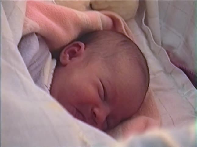 An adorable newborn baby sleeps peacefully, swaddled in cozy blankets