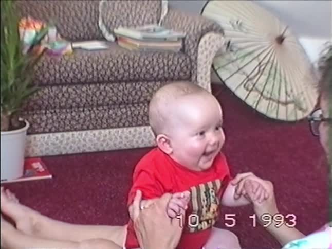 A vintage home video from 1993 shows an adorable baby bursting into laughter while playing with an adult on the living room floor