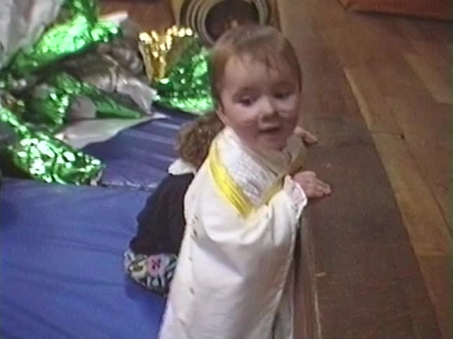 Adorable toddler dressed in a costume with face paint smiles and bounces with joy indoors