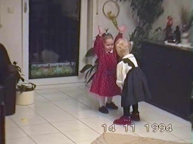 Vintage 1994 home video captures two cute toddler girls in dresses dancing and playing together in the living room