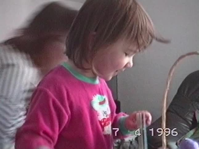 A little girl joyfully inspects a CD she received in her Easter basket in a home video from 1996