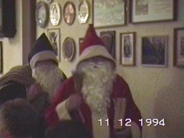 Vintage VHS footage shows two men in Santa Claus costumes drinking at a Christmas party in 1994
