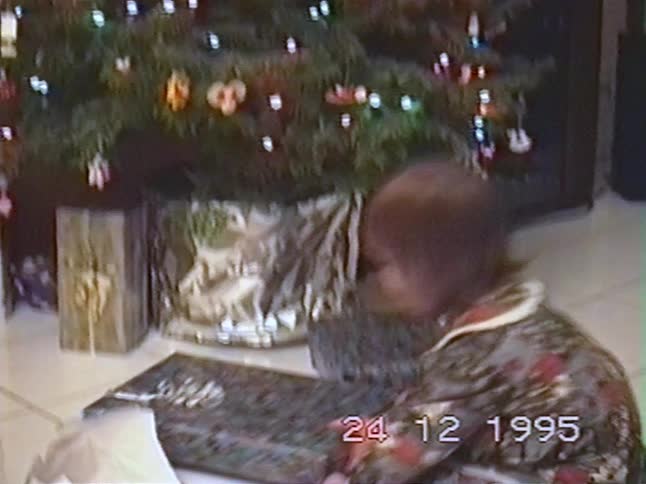 A vintage VHS recording from Christmas Eve 1995 shows an excited little girl dancing around the tree and opening her presents