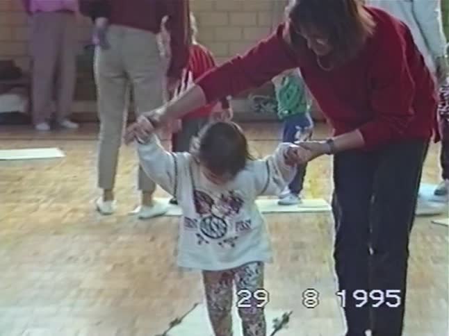 Vintage 1995 footage shows a mother helping her toddler daughter during a parent-child gym class
