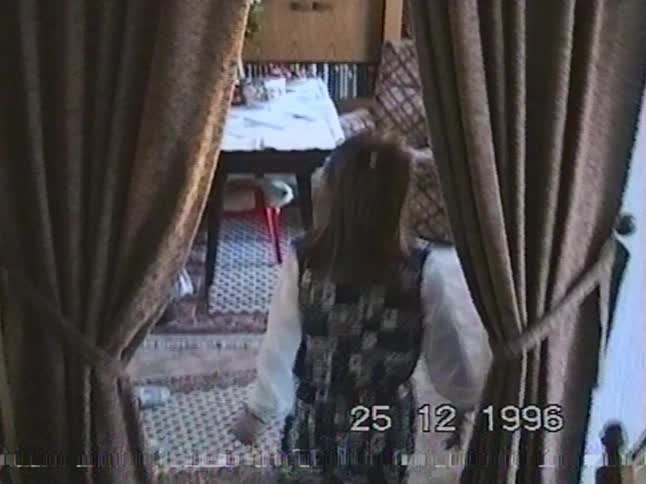 A shy little girl smiles at the camera on Christmas Day 1996 in a sweet home video