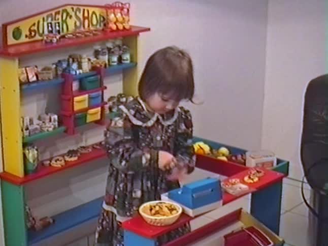 A cute little girl plays cashier at her colorful toy supermarket in this nostalgic home video from the 1990s