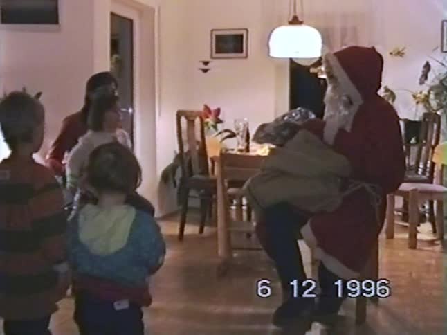 Vintage 1996 home video of Santa Claus visiting a home to give presents to excited children on St. Nicholas' Day