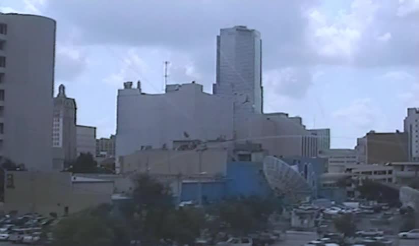 A slow-moving shot reveals the vintage downtown city skyline of Miami, Florida on a cloudy day in 1989