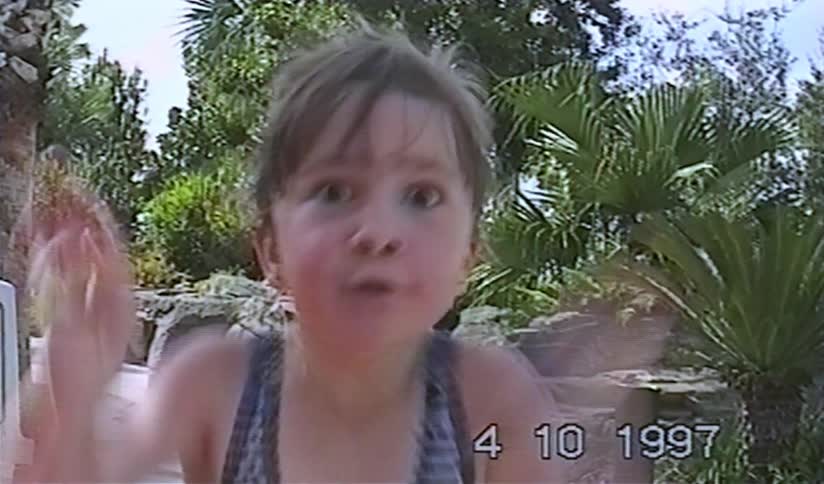 An adorable little girl with wide eyes babbles excitedly at the camera in a nostalgic home video from 1997