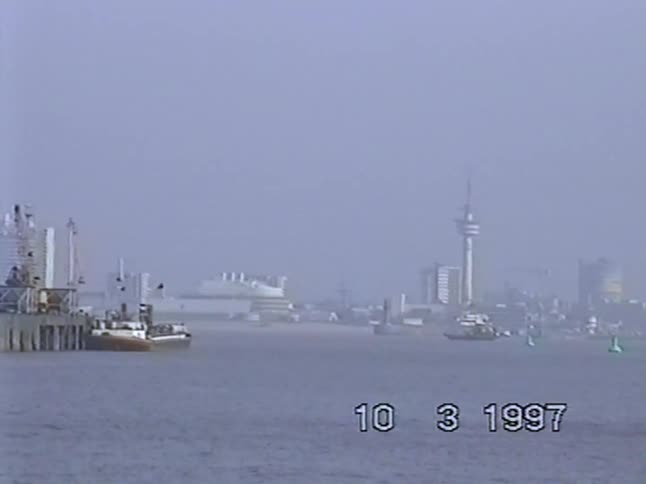 A slow pan across the industrial Port of Rotterdam reveals the Euromast through the haze in this archival footage from 1997