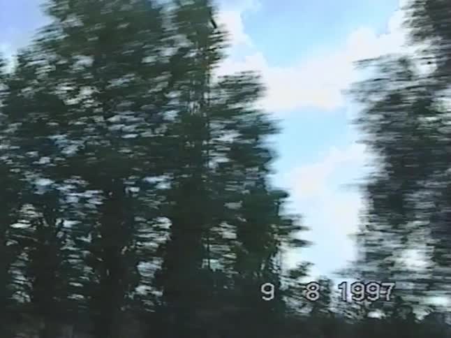 A vintage 1997 VHS point-of-view shot from a moving car captures the iconic Funkturm Berlin radio tower against a cloudy sky