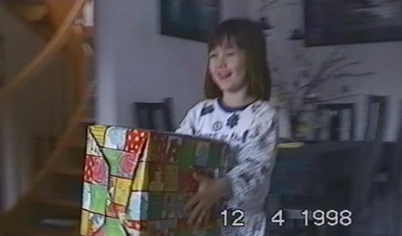 A smiling little girl proudly carries her big Easter present into the room in this nostalgic 1998 home video