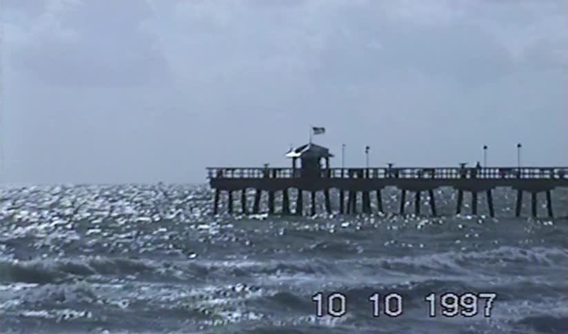 Vintage VHS footage from 1997 shows a slow zoom into a long pier over the shimmering ocean