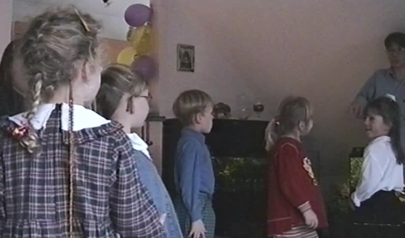 Vintage 90s VHS footage shows a group of children at a birthday party, with one excited girl jumping up and down