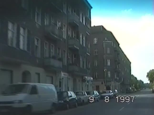 Driving slowly past old European apartment buildings on a quiet city street in 1997