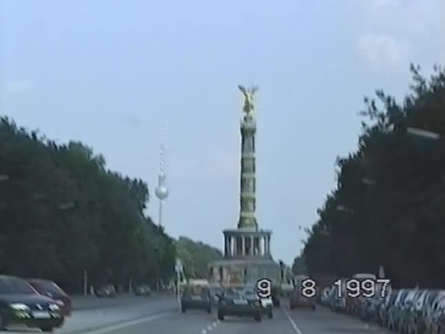 A vintage 1997 VHS shot captures the iconic Berlin Victory Column with the TV Tower visible in the background as traffic moves along the street