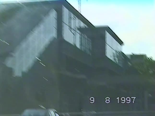 A vintage VHS point-of-view shot from a car driving past an elevated U-Bahn train station in 1997