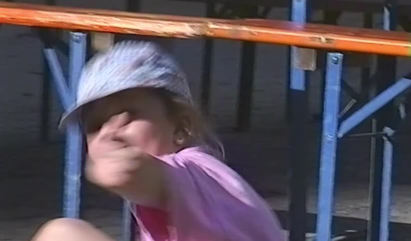 Vintage VHS footage of a cute little girl in a pink shirt making silly faces for the camera outdoors