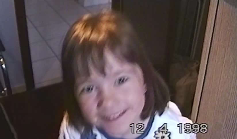 A smiling young girl's face is revealed from a pixelated screen in a nostalgic home video from 1998