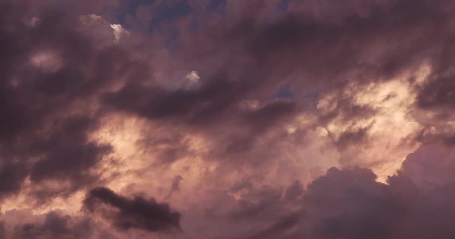 Stormy purple and pink clouds gather in a dramatic and colorful sunset sky
