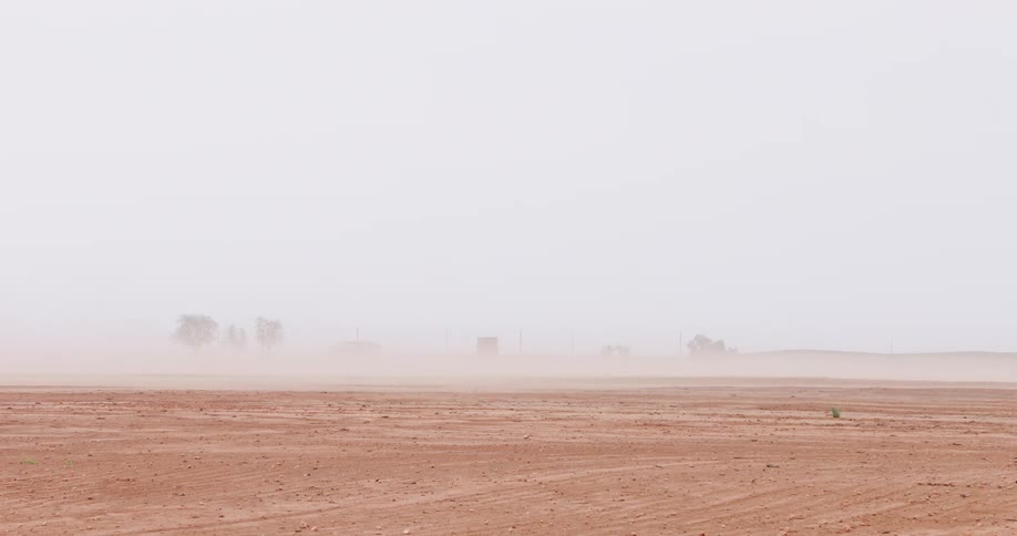A massive sandstorm sweeps across a barren and dry desert landscape